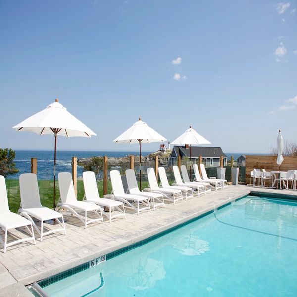 阳光明媚的日子里，湖边的游泳池里有白色沙滩椅