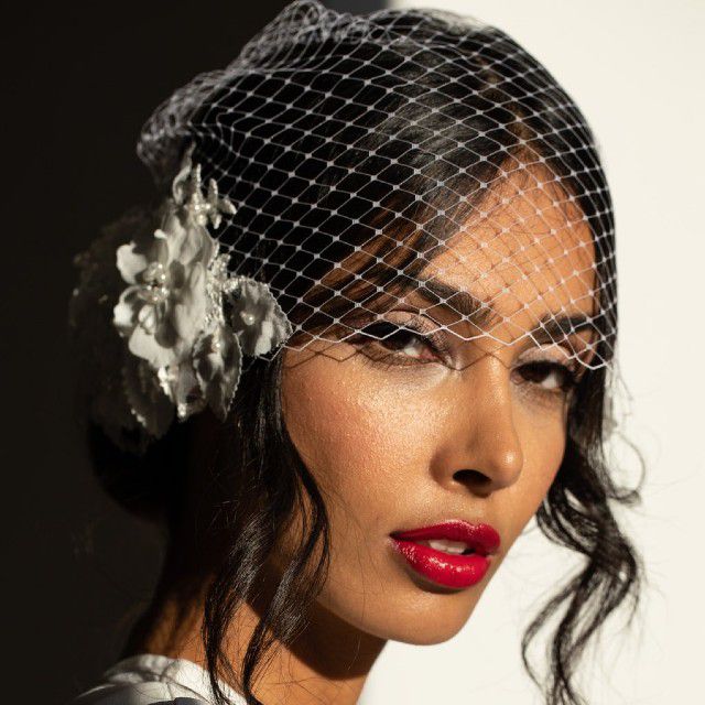 新娘涂着红色的口红，戴着带花的鸟笼面纱