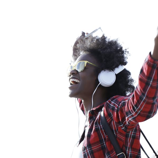 快乐的年轻女子听音乐与耳机和手机