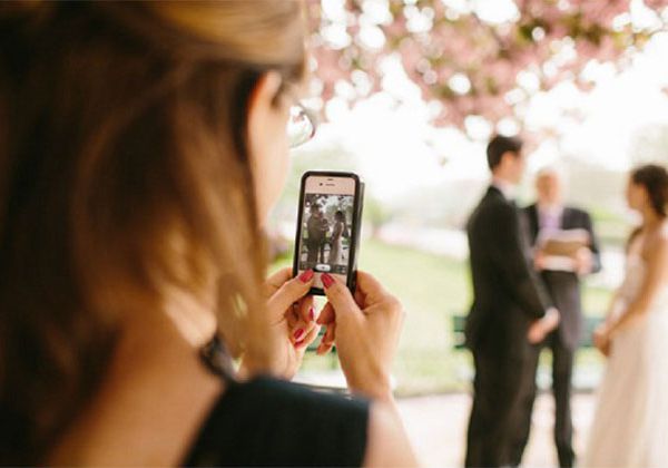 新娘和新郎在电话的游客拍照