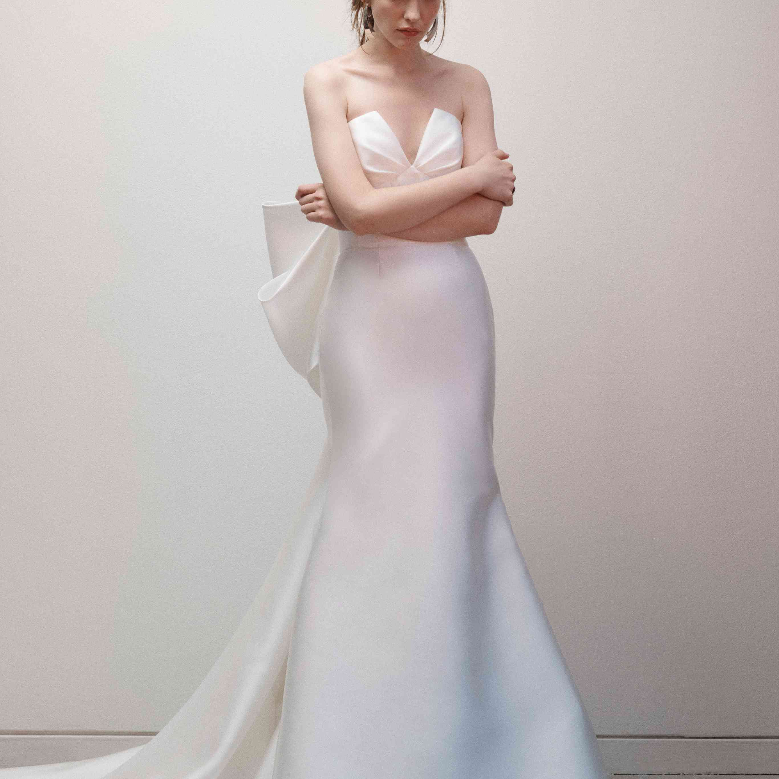模特身穿无肩带喇叭礼服，v领，背部有大蝴蝶结