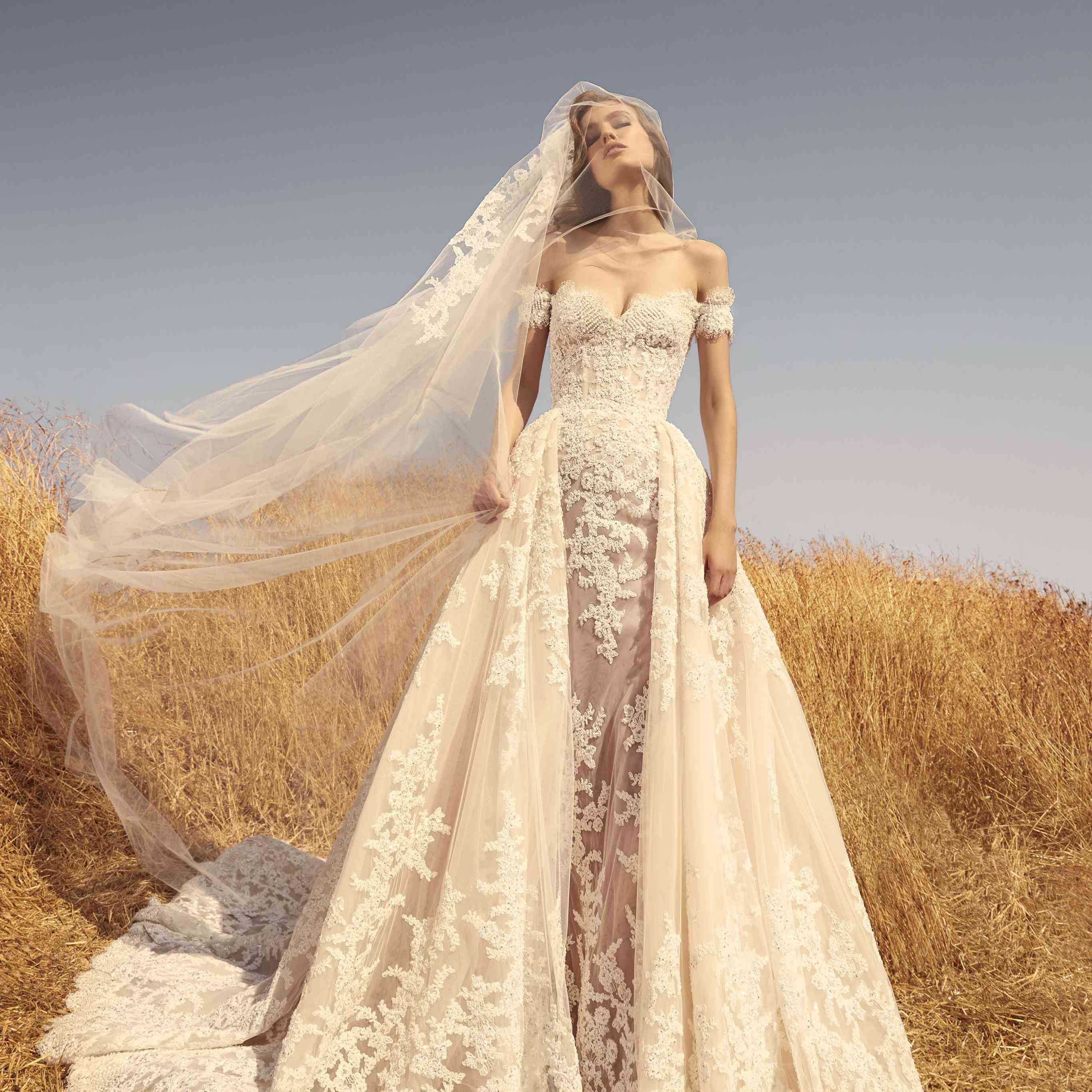 模型n了肩膀壳薄纱礼服装饰着刺绣的白色蕾丝贴花和一个匹配的面纱