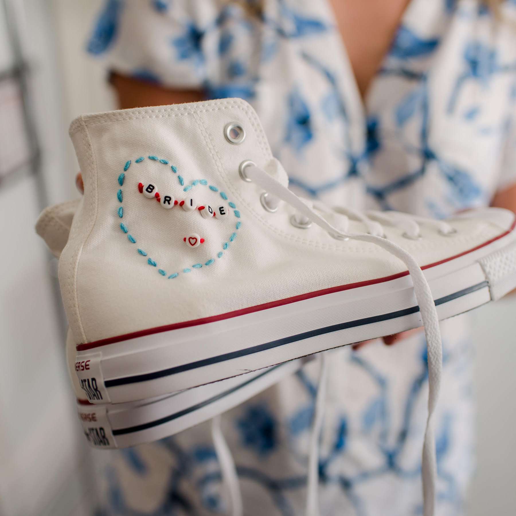 拿着一个白色逆转运动鞋的新娘与“新娘”缝了与珠子