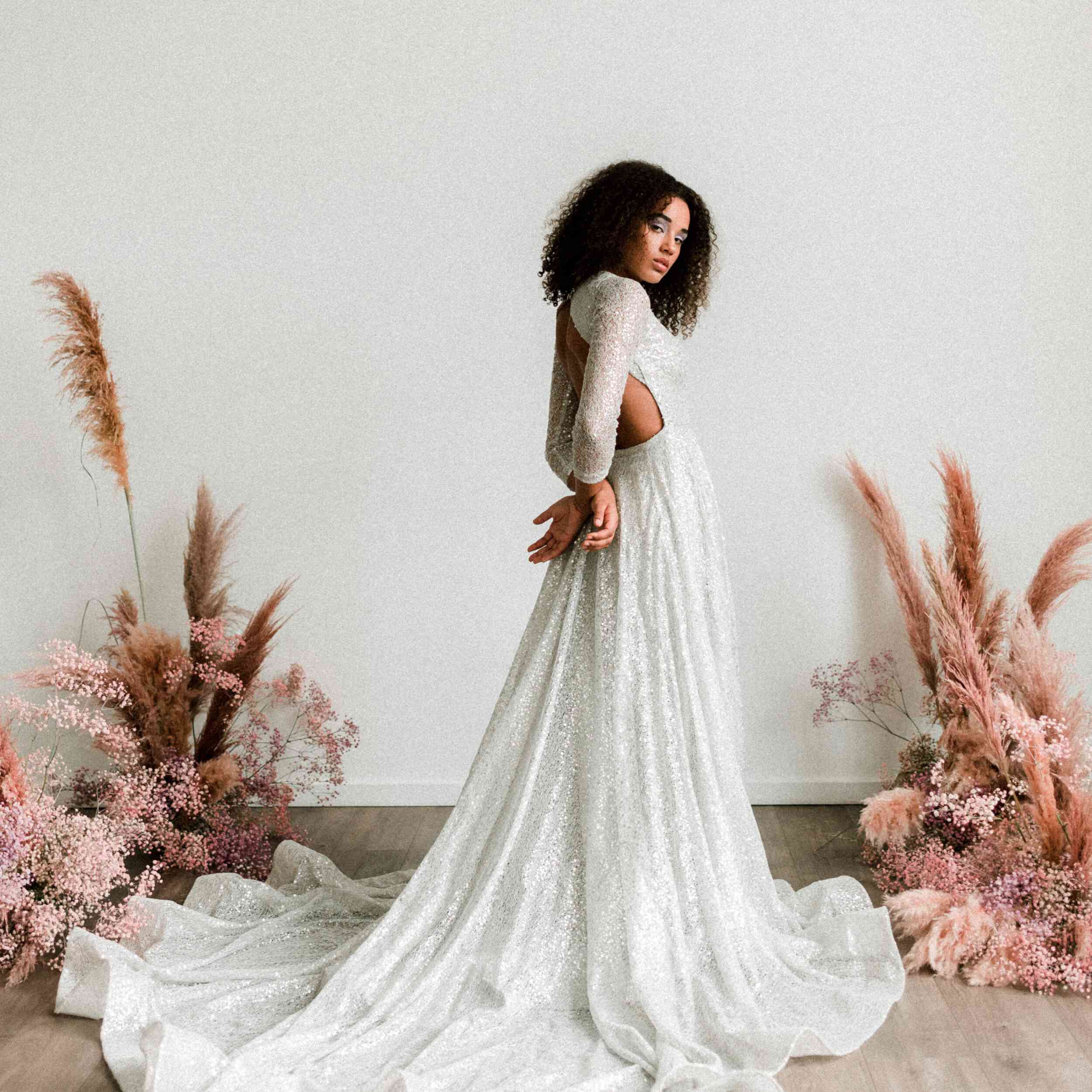 身穿银色亮片礼服的模特站在一旁，双手放在背后