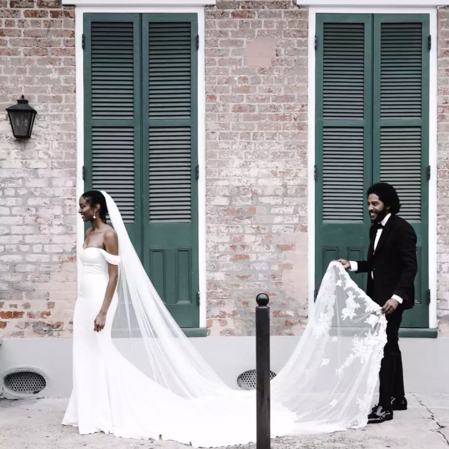 丈夫捧着新娘的教堂般长的面纱