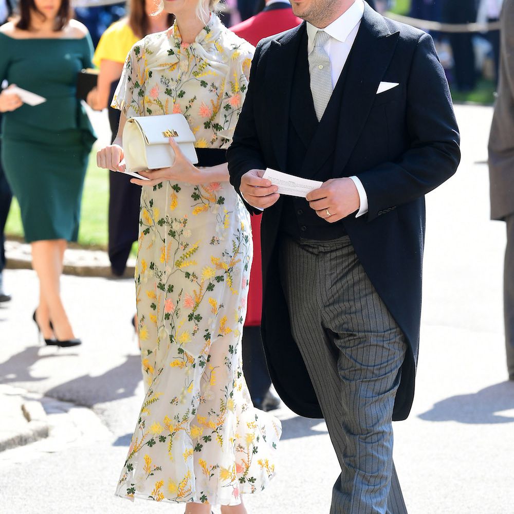 凯瑞·穆里根面带微笑地出席了皇室婚礼，她身穿印花长裙，灰色高跟鞋，丈夫马库斯·芒福德身穿深色西装外套和条纹休闲裤站在她身边。
