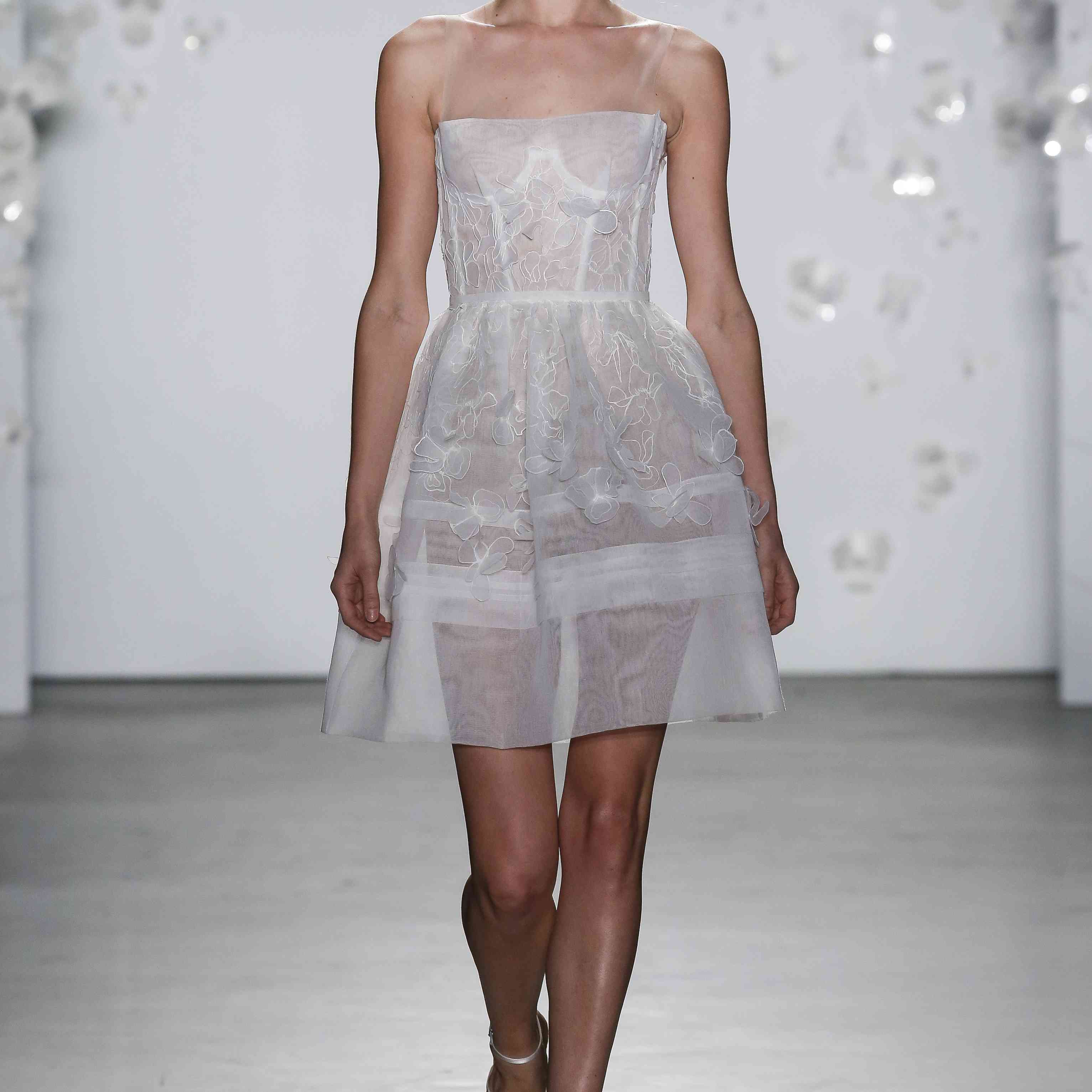 模特穿着带有花卉刺绣的薄纱短婚纱