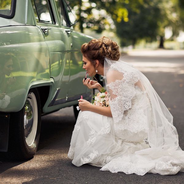 新娘在车上涂口红的侧面照片