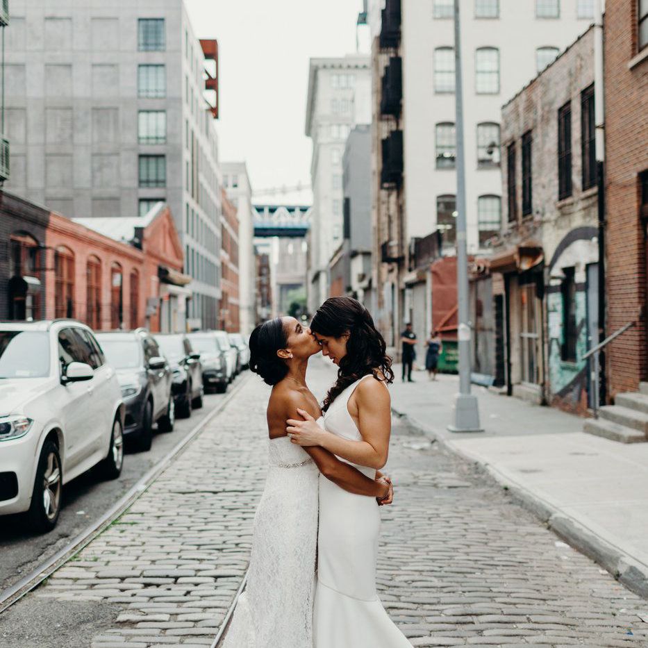 亲吻她的新娘额头的新娘在城市街道上站立