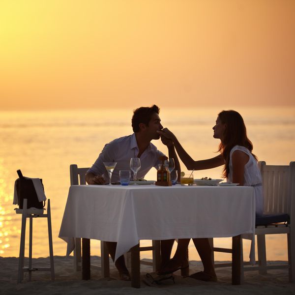 一对夫妇在海滩上享受浪漫的日落晚餐