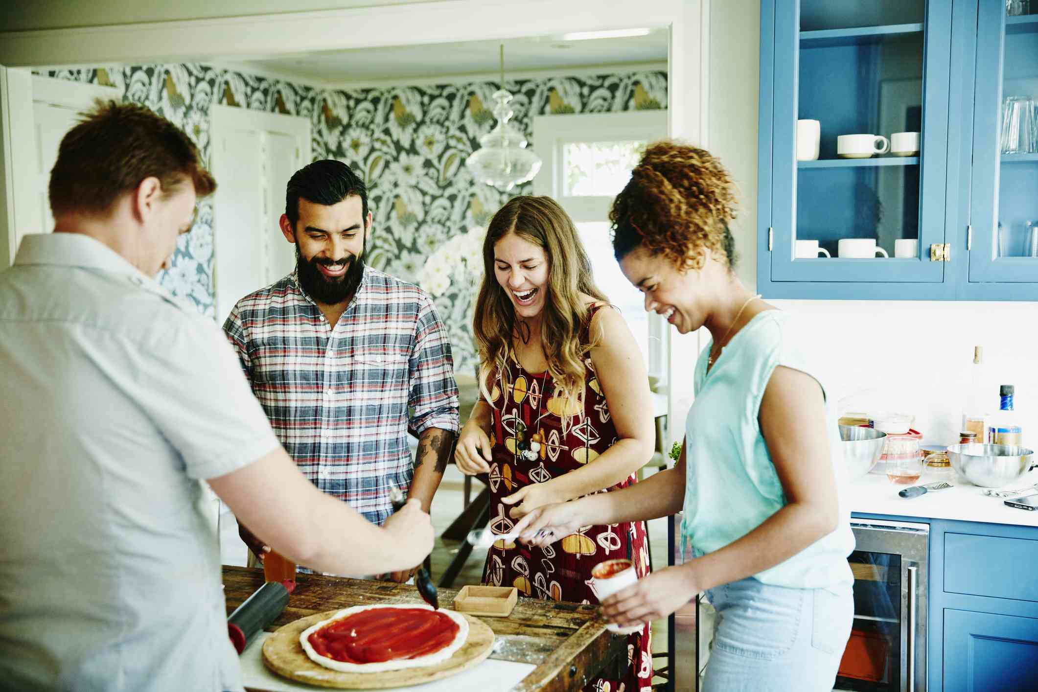 一起准备薄饼的笑的小组在厨房里