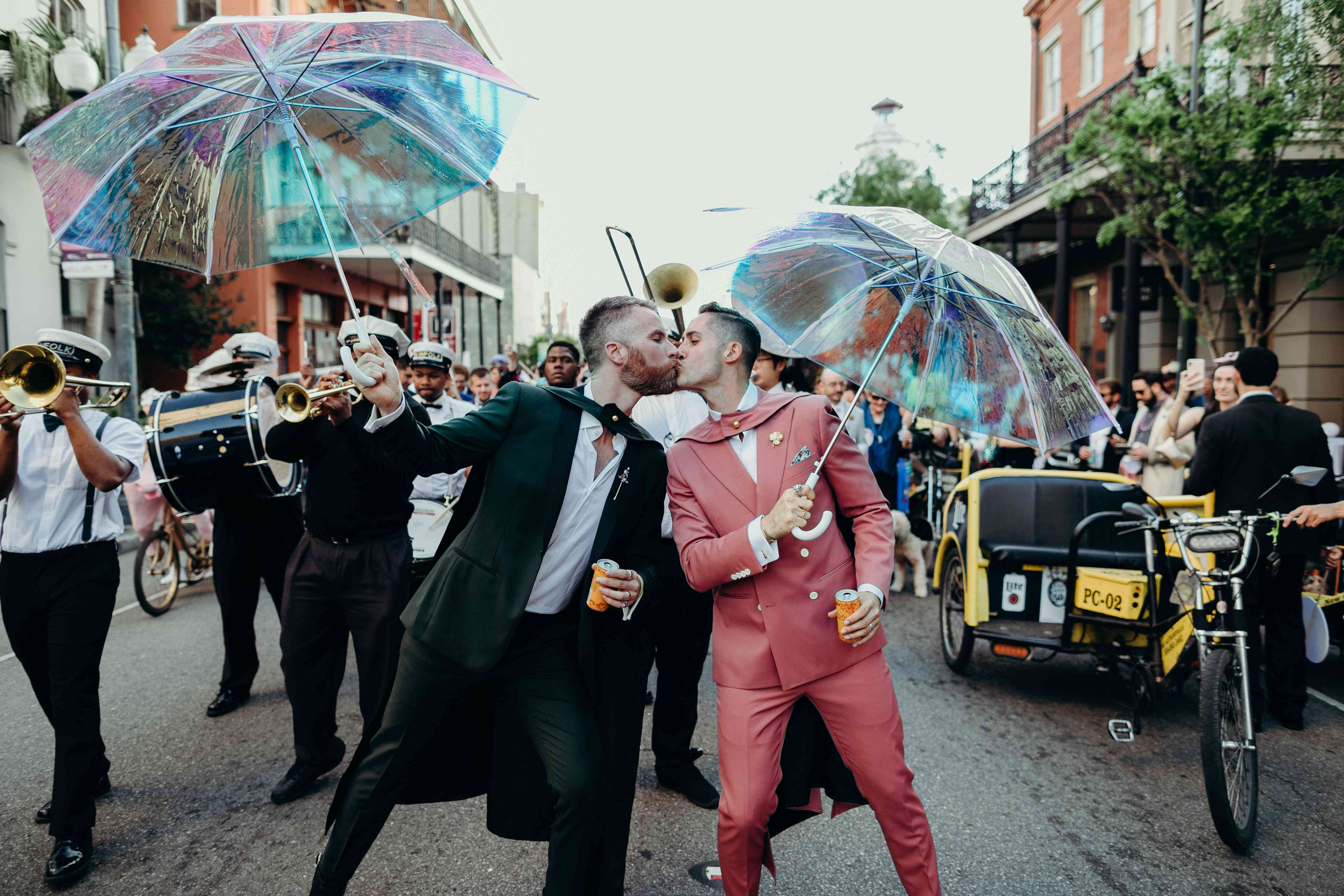 亲吻在他们的婚礼之日的两个新郎在新奥尔良与游行在背景中