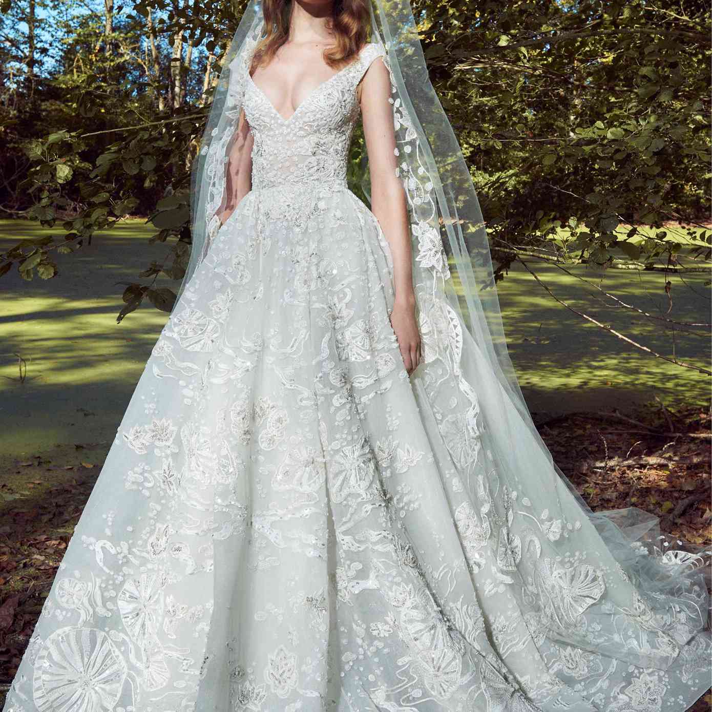 模型在一个露肩v领轻舟舞会礼服和刺绣和珠饰和一个匹配的面纱