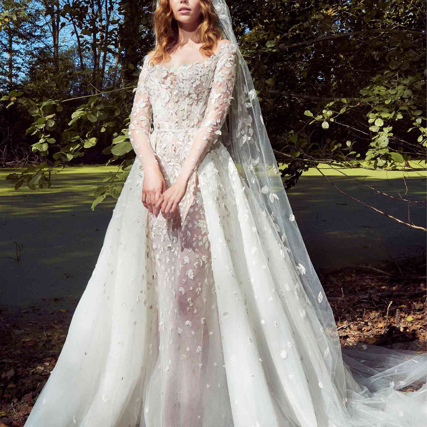 模型在露肩长袖礼服印花布花贴花和一个匹配的半裙和面纱