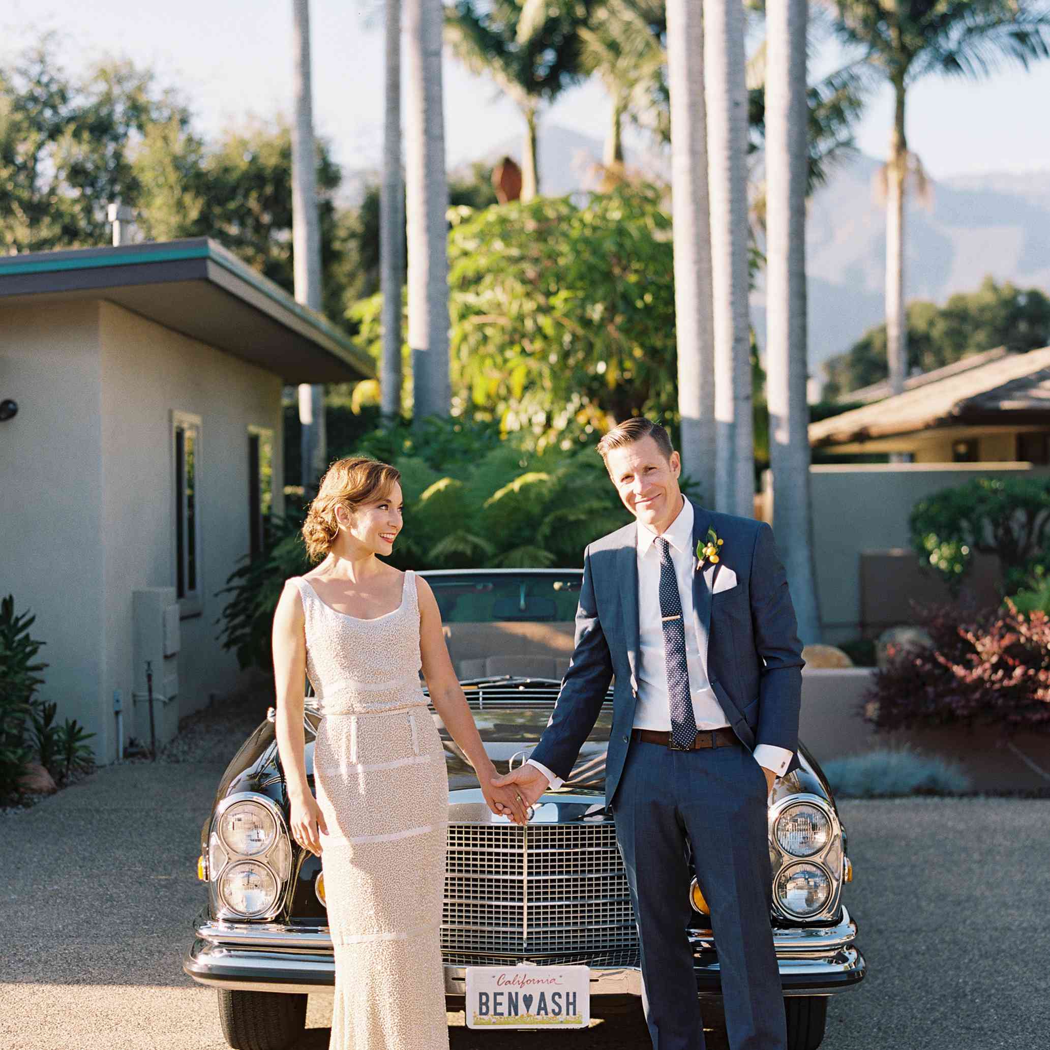 站立在汽车前面的新娘和新郎