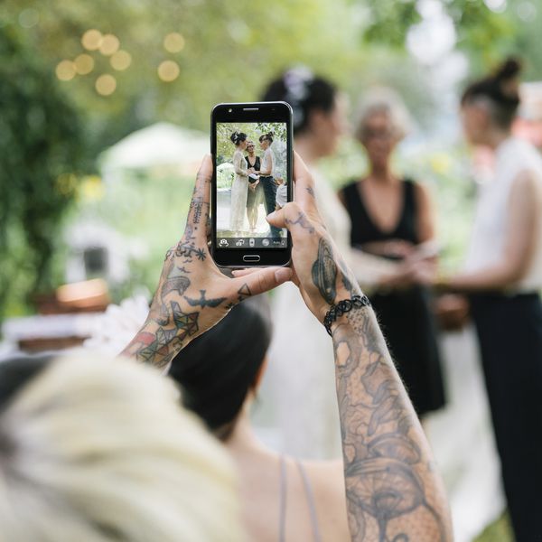 使用智能手机的纹身花刺妇女拍照片在婚礼