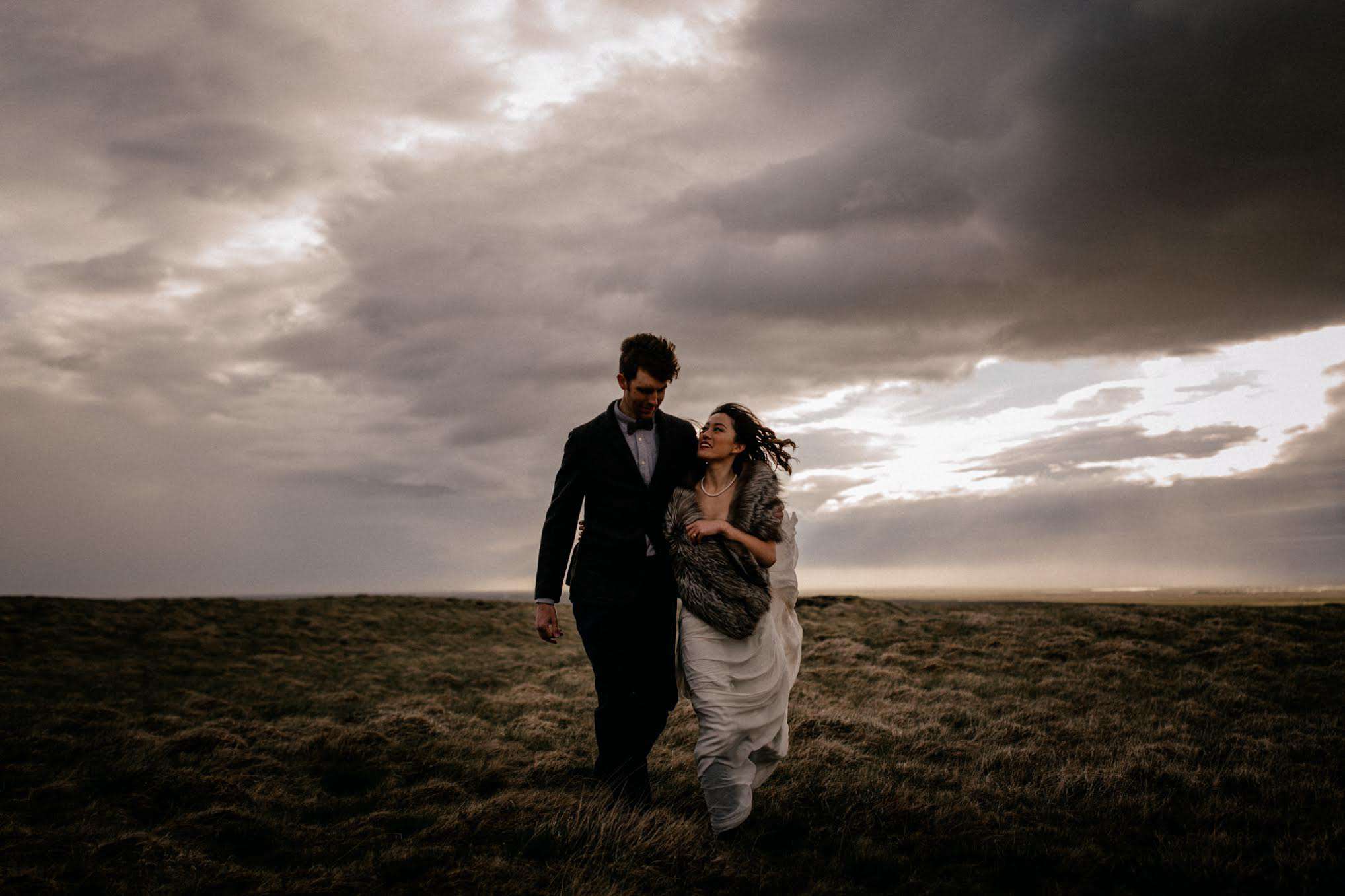 夫妇走在冰岛他们背后一个惊人的天空