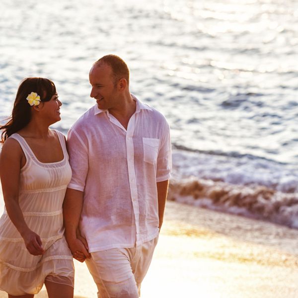 一对情侣在夏威夷的海滩上散步”class=