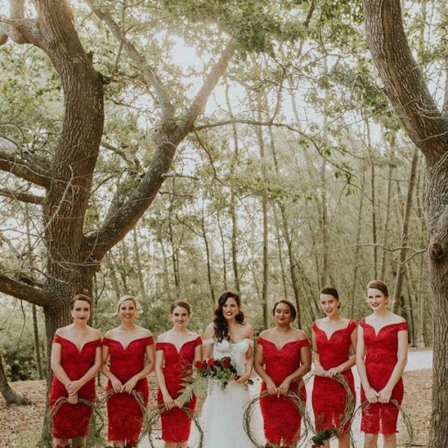 在拿着绿叶花圈的红色礼服的伴娘