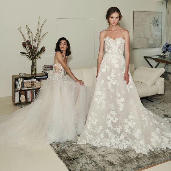 一个模特穿着婚纱坐在客厅，另一个穿着婚纱站在客厅