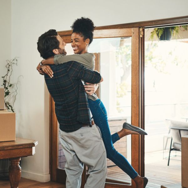 一个深情的中年男子举起他的妻子在他们的新家庆祝