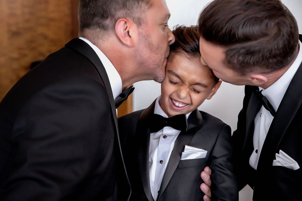 两个新郎亲吻他们儿子的额头