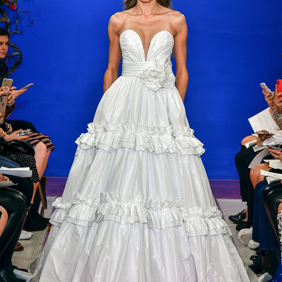 模特在无肩带降落伞塔夫绸舞会礼服与分层褶边裙走秀