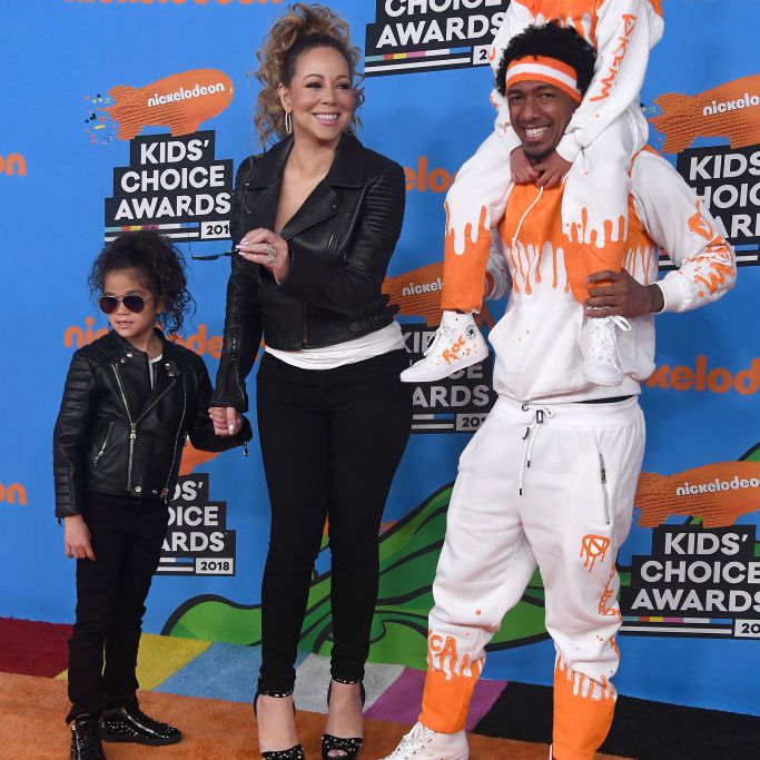 玛丽亚凯莉和尼克大炮穿着与他们的双胞胎在橙色地毯上戴着匹配的服装，为孩子选择奖