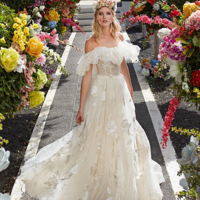 模特在绣花薄纱透明舞会礼服与3-D玫瑰图案，透明胸衣褶裙和褶边细节突出的肩膀