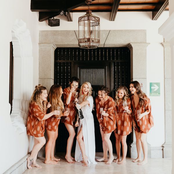 新娘和伴娘站在门口，手里拿着香槟和酒杯