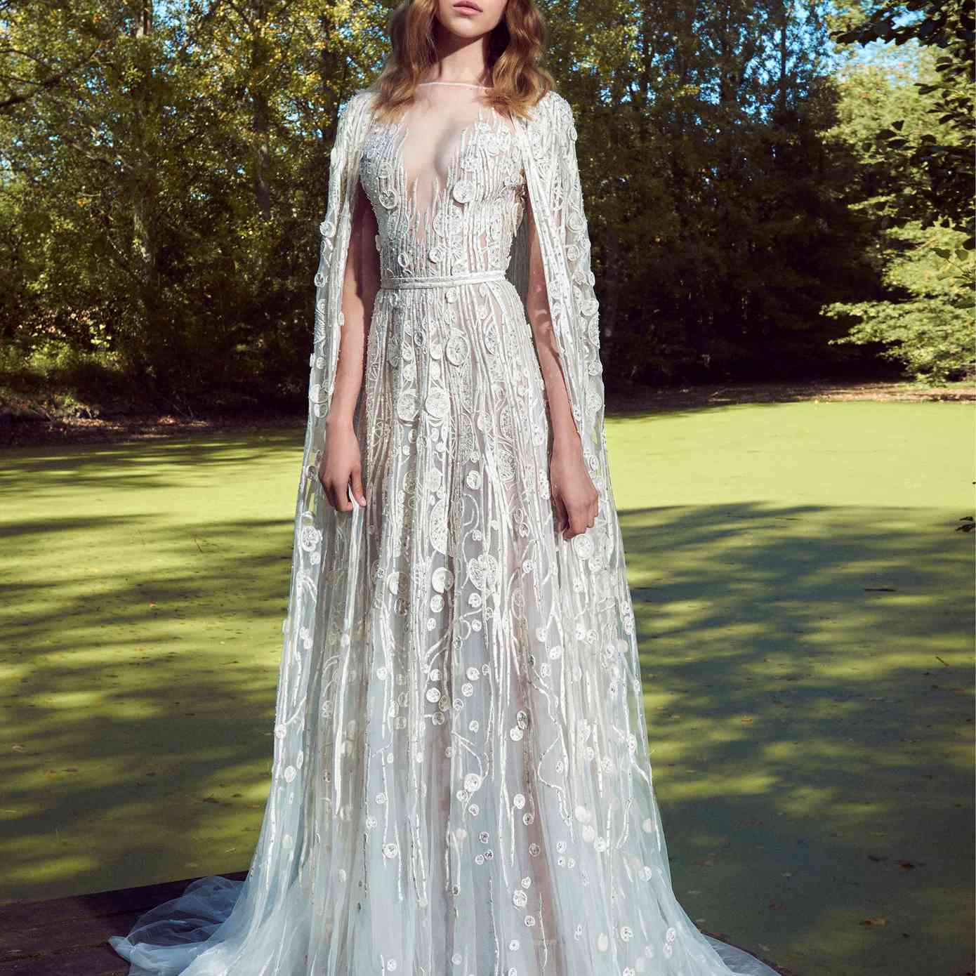 模型与幻觉短袖船领裙礼服领口,串珠刺绣贴花和一个匹配的垂至地板的斗篷