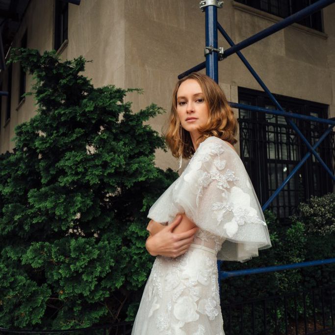 模特身着薄纱礼服，饰以花卉和珍珠，配以披肩