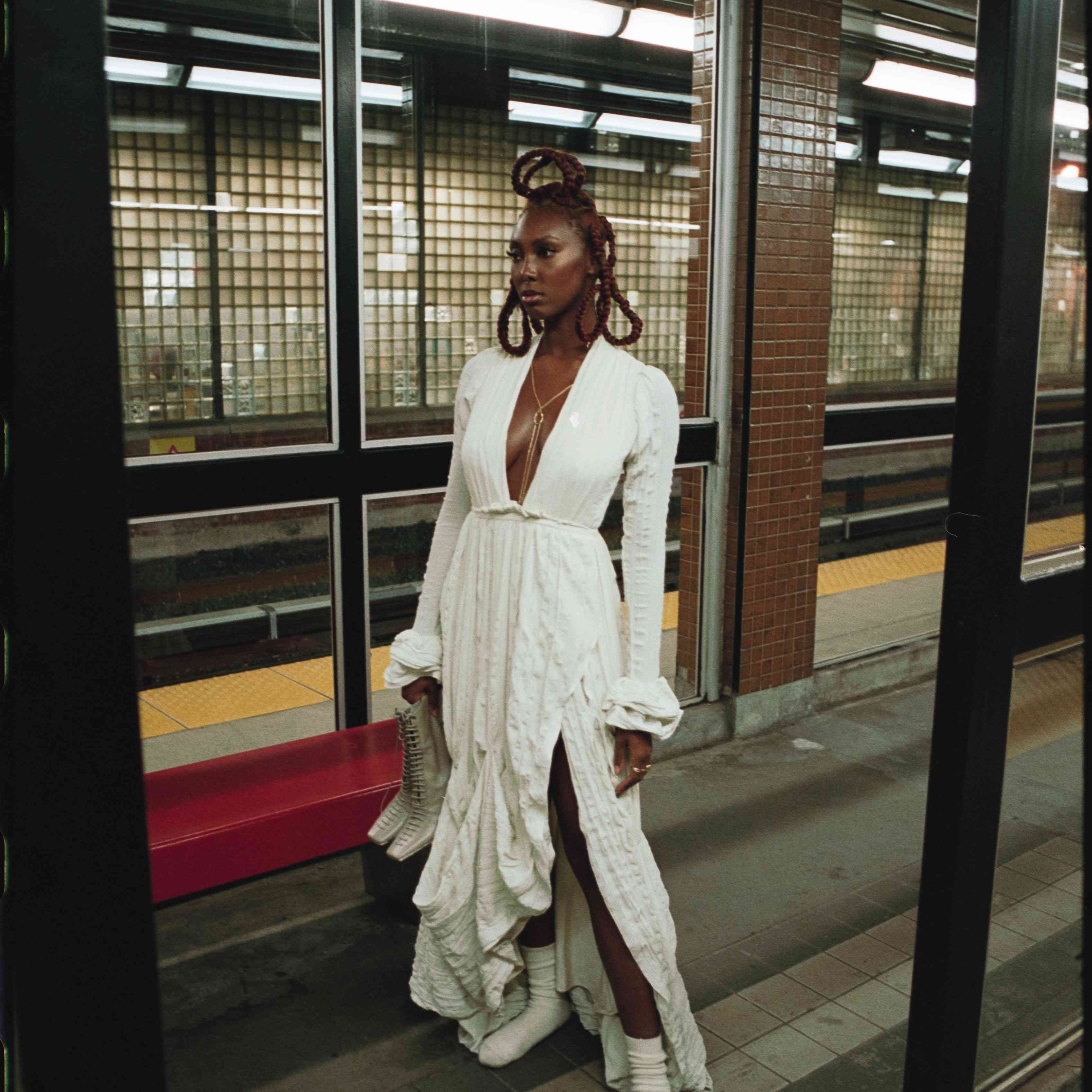 一个女人穿着婚纱站在地铁站里。