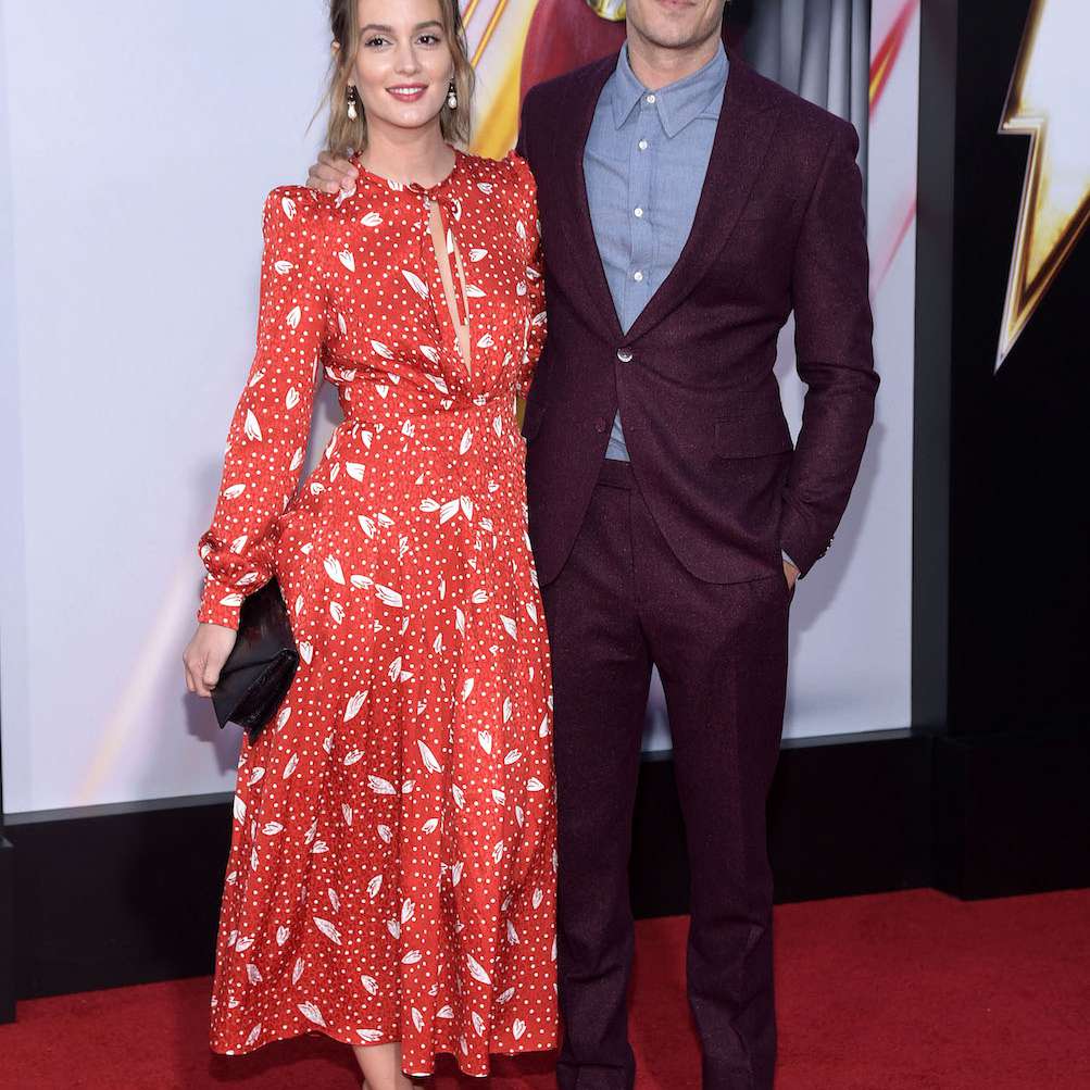 Leighton Meester穿着一件大胆的红印花衣服，同时沿着亚当布罗迪的手臂走红地毯。