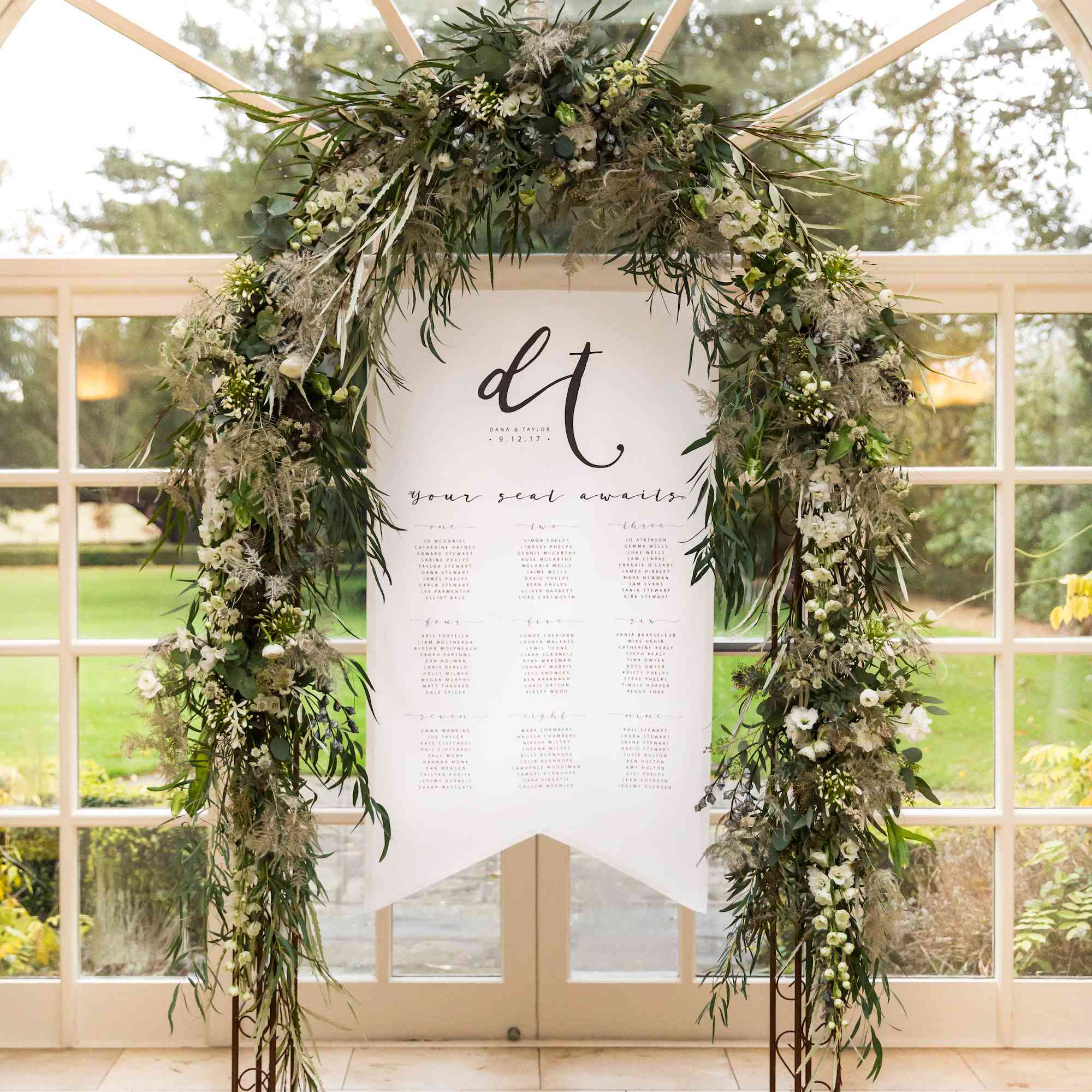 一个室内婚礼与挂在玻璃门和拱形窗口前面的叶子曲拱的白色婚礼横幅