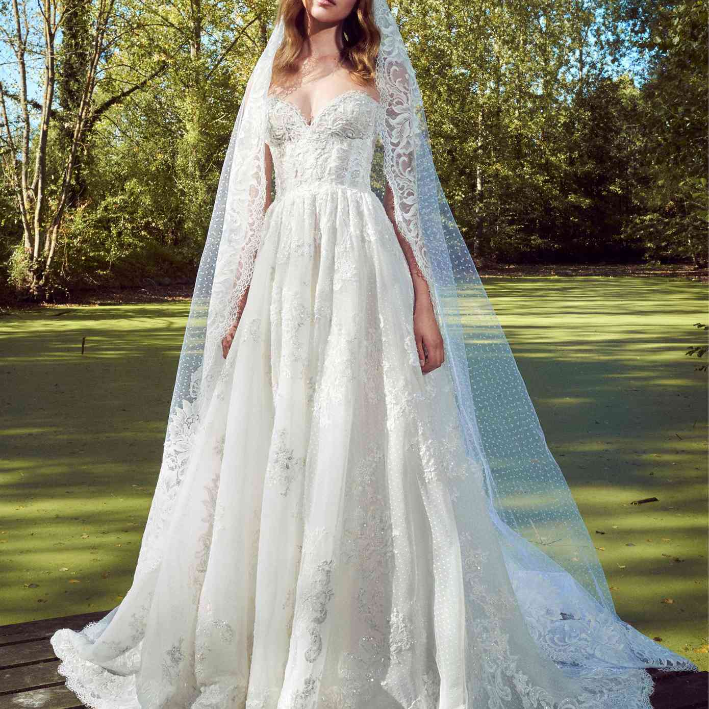 模型在无肩带甜心点缀薄纱礼服公主串珠花边刺绣和虚线薄纱莱与睫毛花边面纱