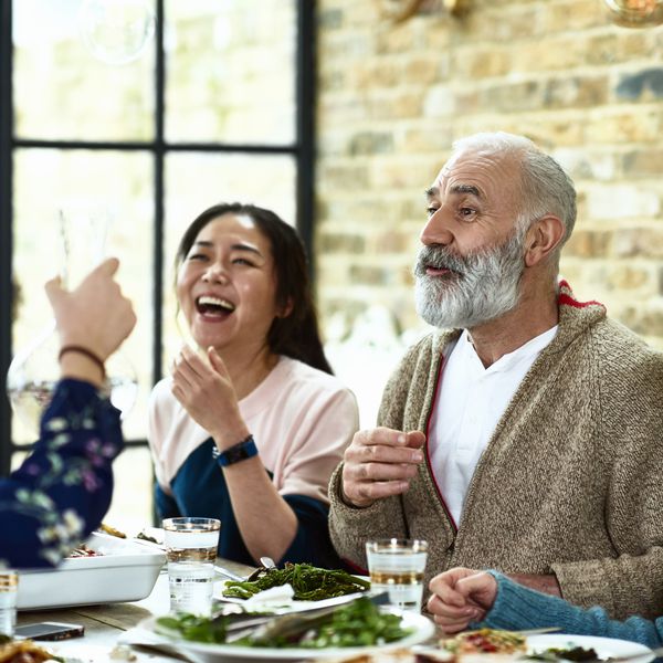 快乐成熟的男人在晚餐时讲故事，家人在笑