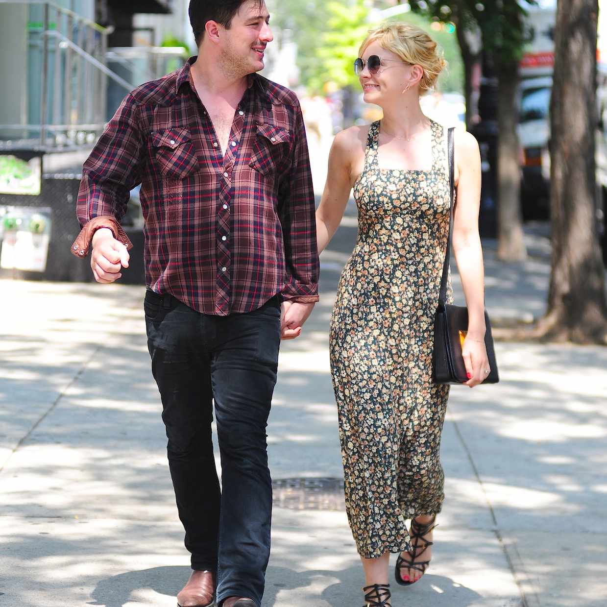 马库斯·芒福德和凯瑞·穆里根手牵着手走在街上，凝视着对方的眼睛