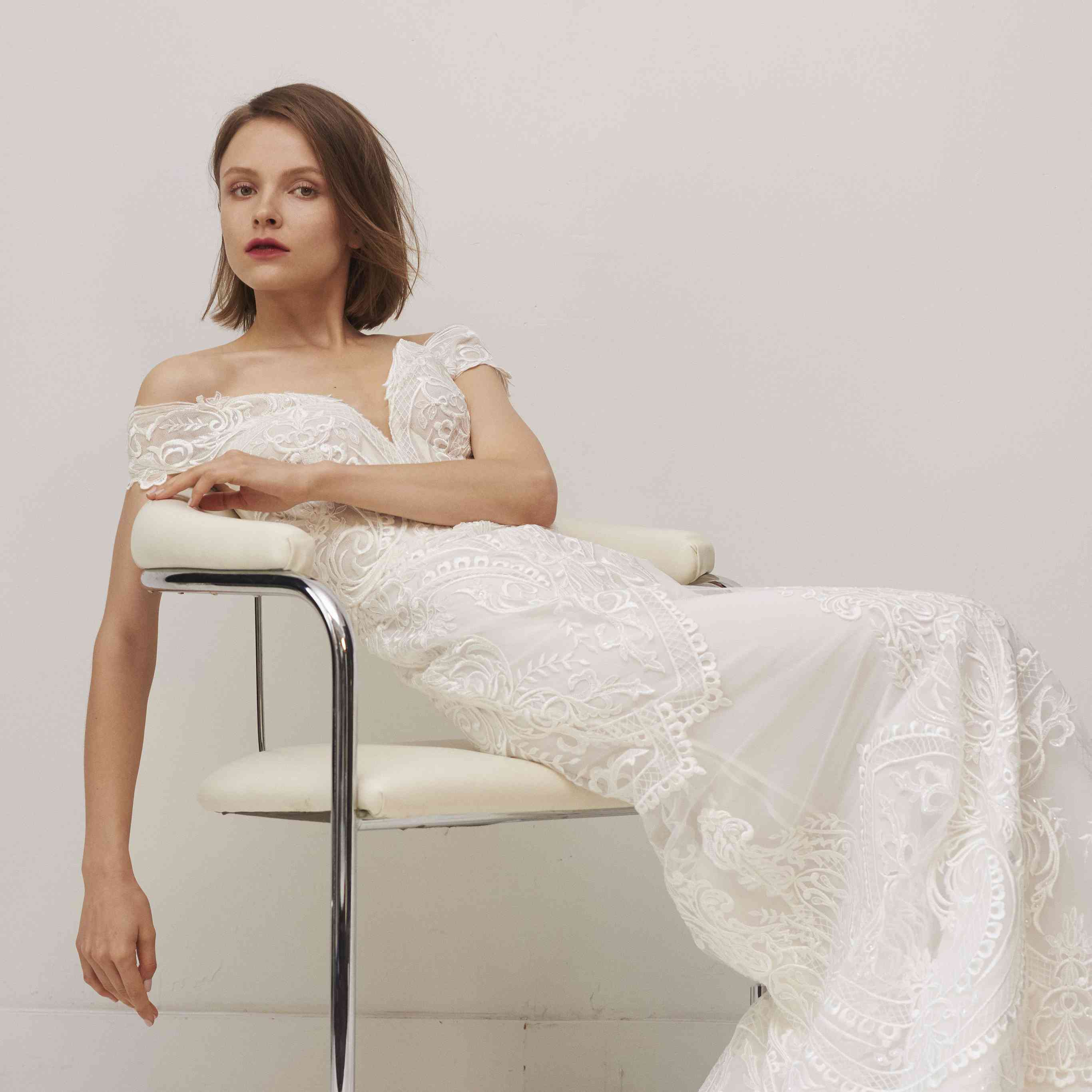 型号坐在椅子上逐渐消失的肩花边的紧身连衣裙