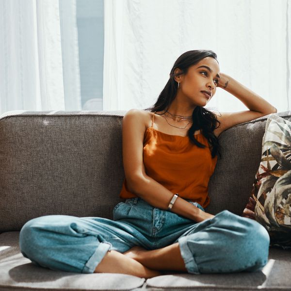 一个女人交叉地坐在沙发上，靠在手上做白日梦