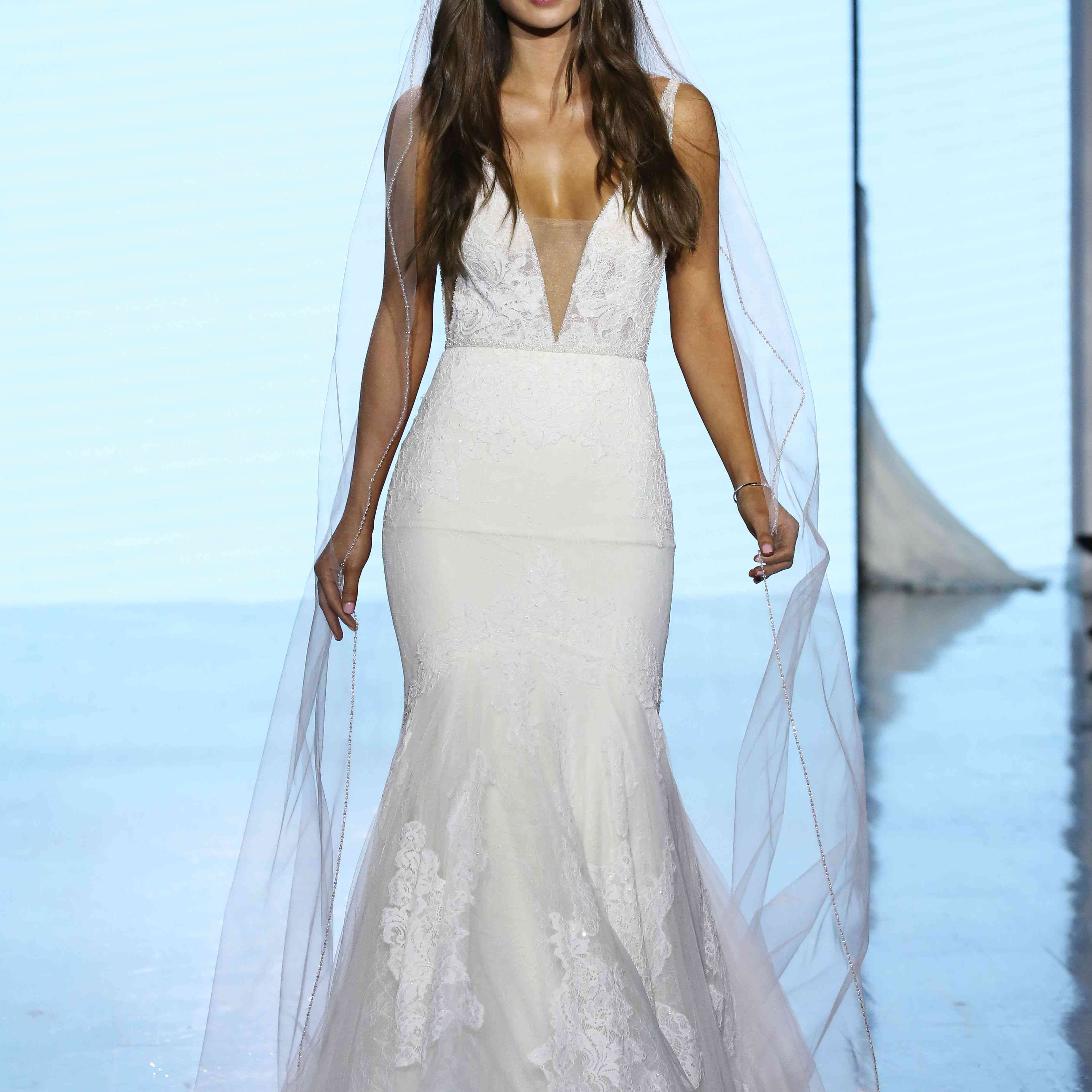 模特在t台上穿着花蕾丝v领喇叭结婚礼服