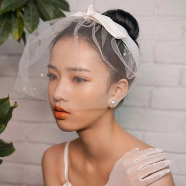 亚洲新娘穿着薄纱鸟笼面纱与蝴蝶结头带