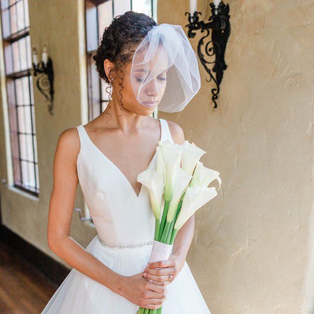 黑色新娘手持鲜花，戴着薄纱鸟笼面纱