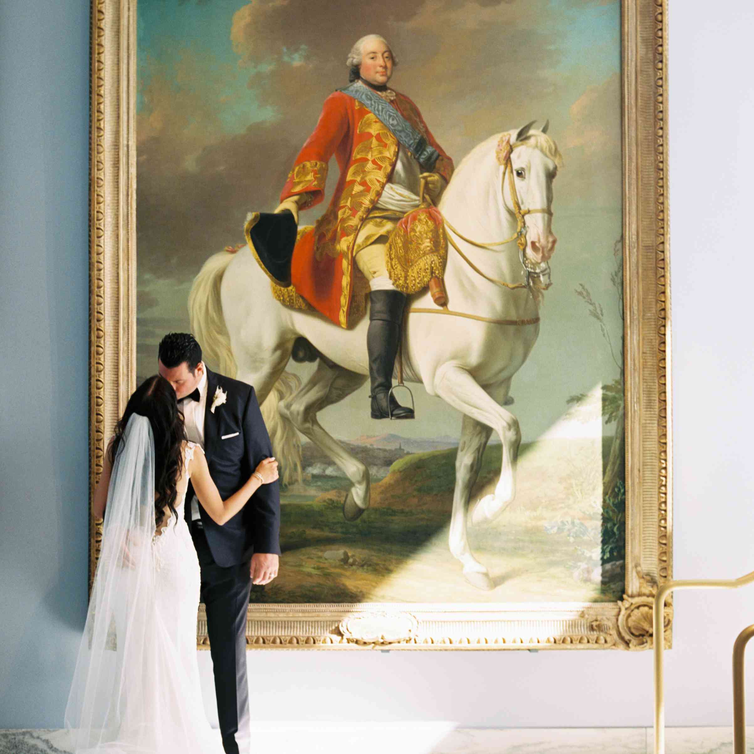 新娘和新郎在一幅画旁边摆好姿势