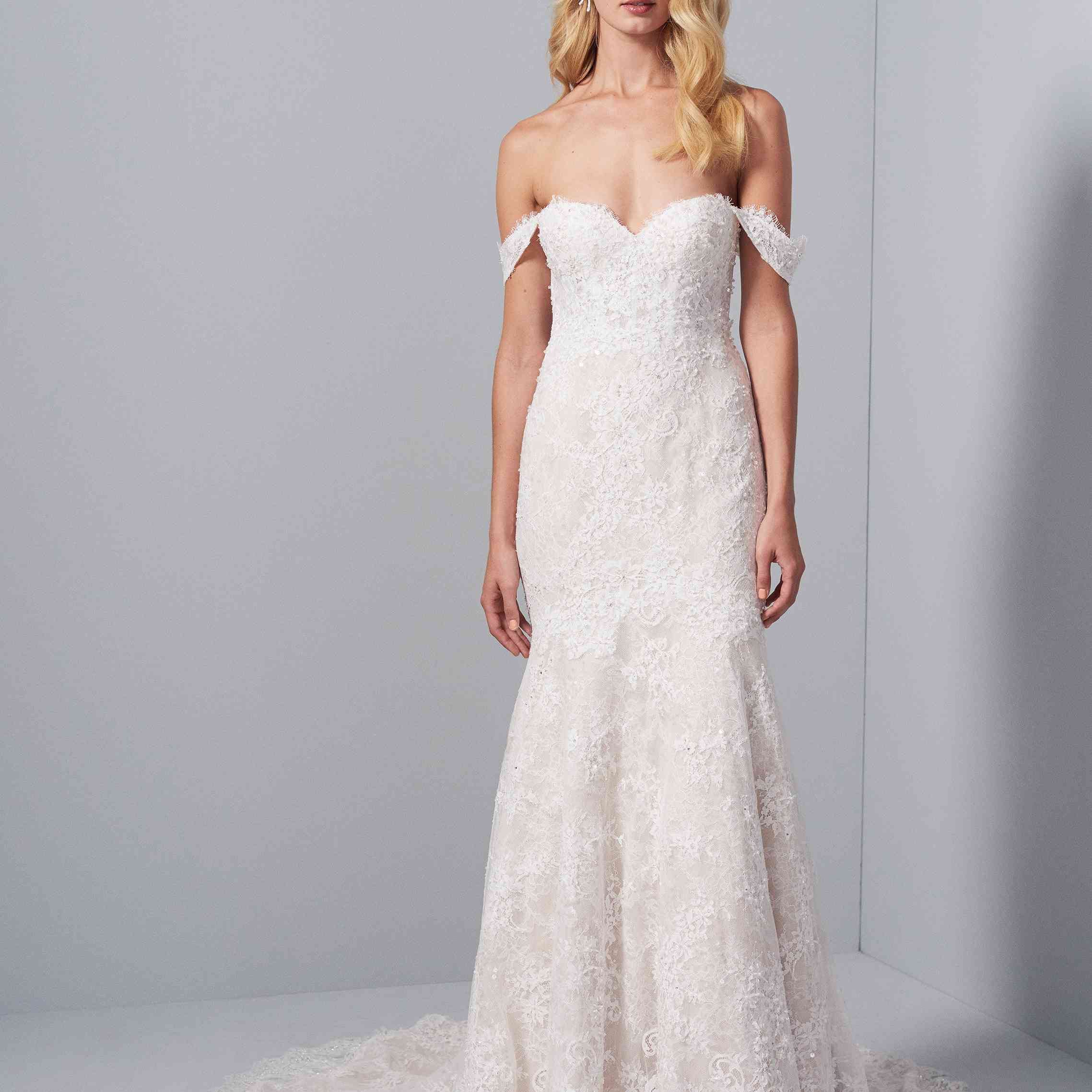 模特在象牙蕾丝装饰的适合和闪光礼服与露肩袖