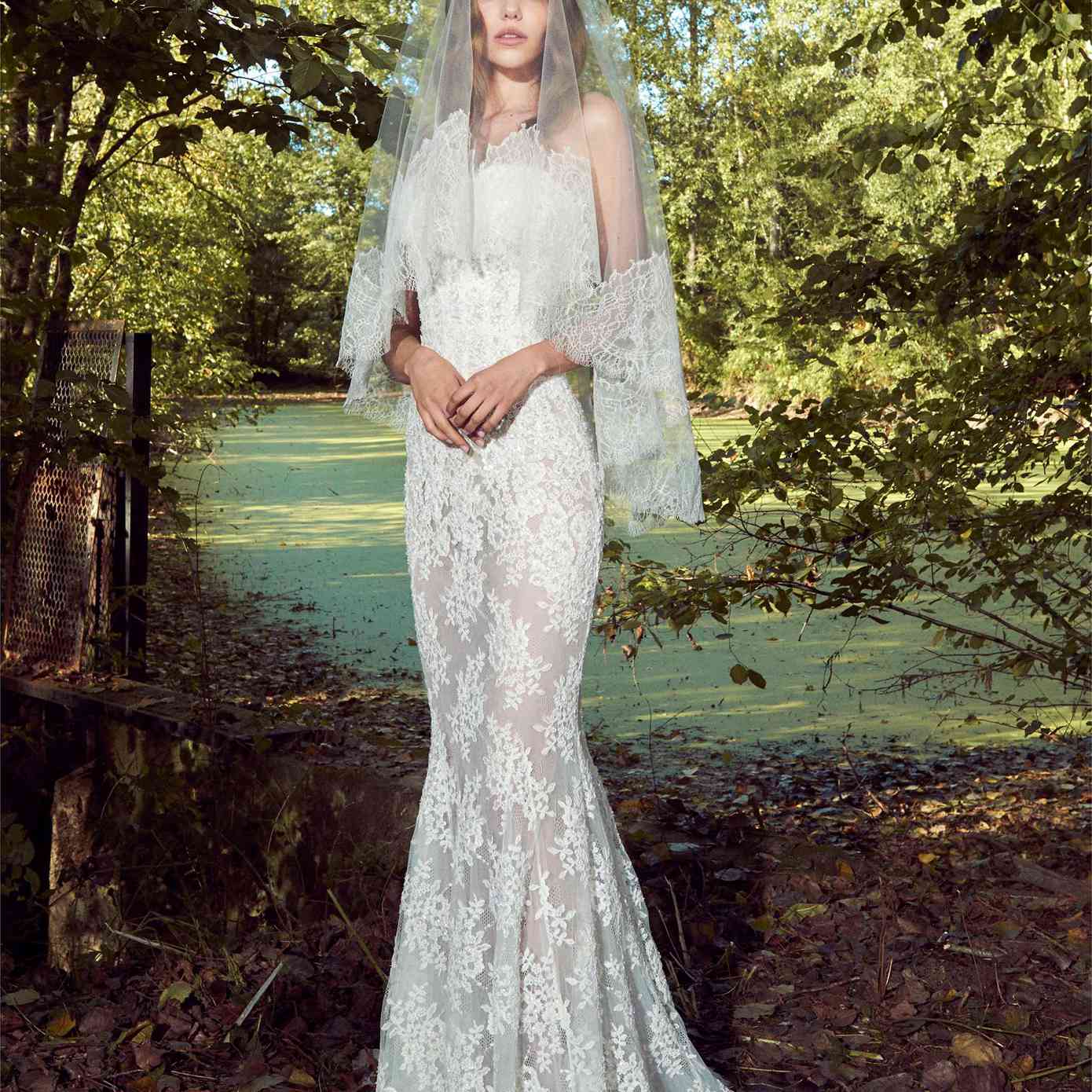 模型在无肩带的薄纱美人鱼礼服,蕾丝刺绣和睫毛花边与匹配的面纱