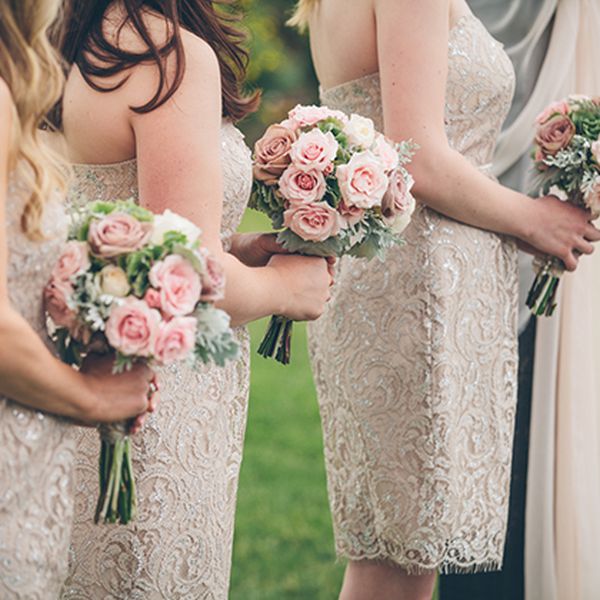 伴娘们穿着中性的短裙，手拿花束排成一排