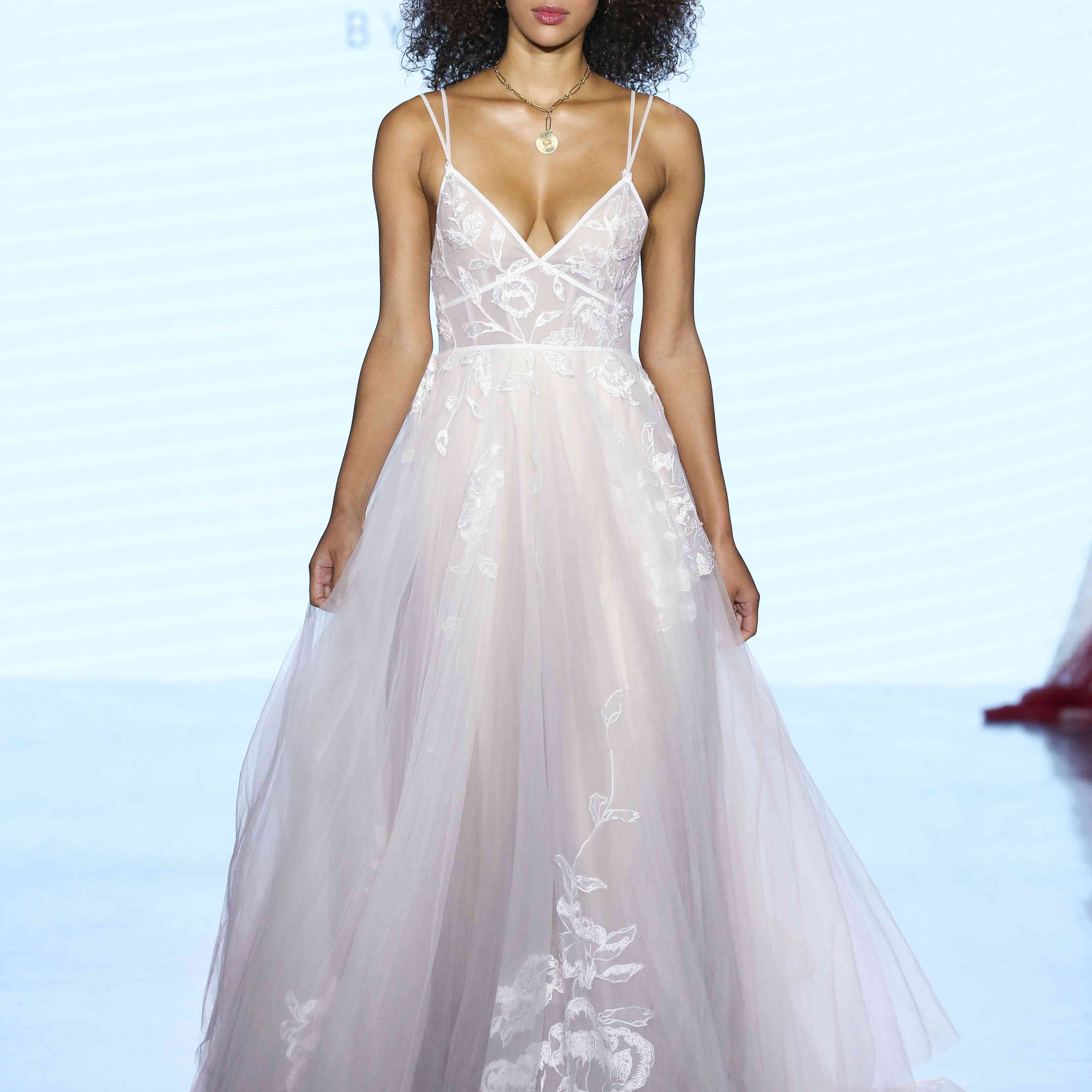 模特在薄纱婚纱与花卉花边刺绣，v领口，和双意大利面条带子