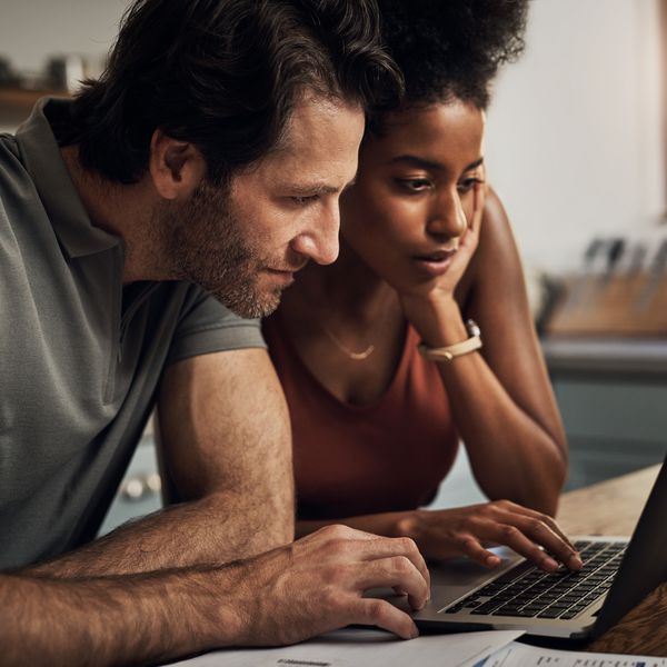 一个深情的年轻夫妇裁剪射击使用一台膝上型计算机，当做他们的预算在家“class=