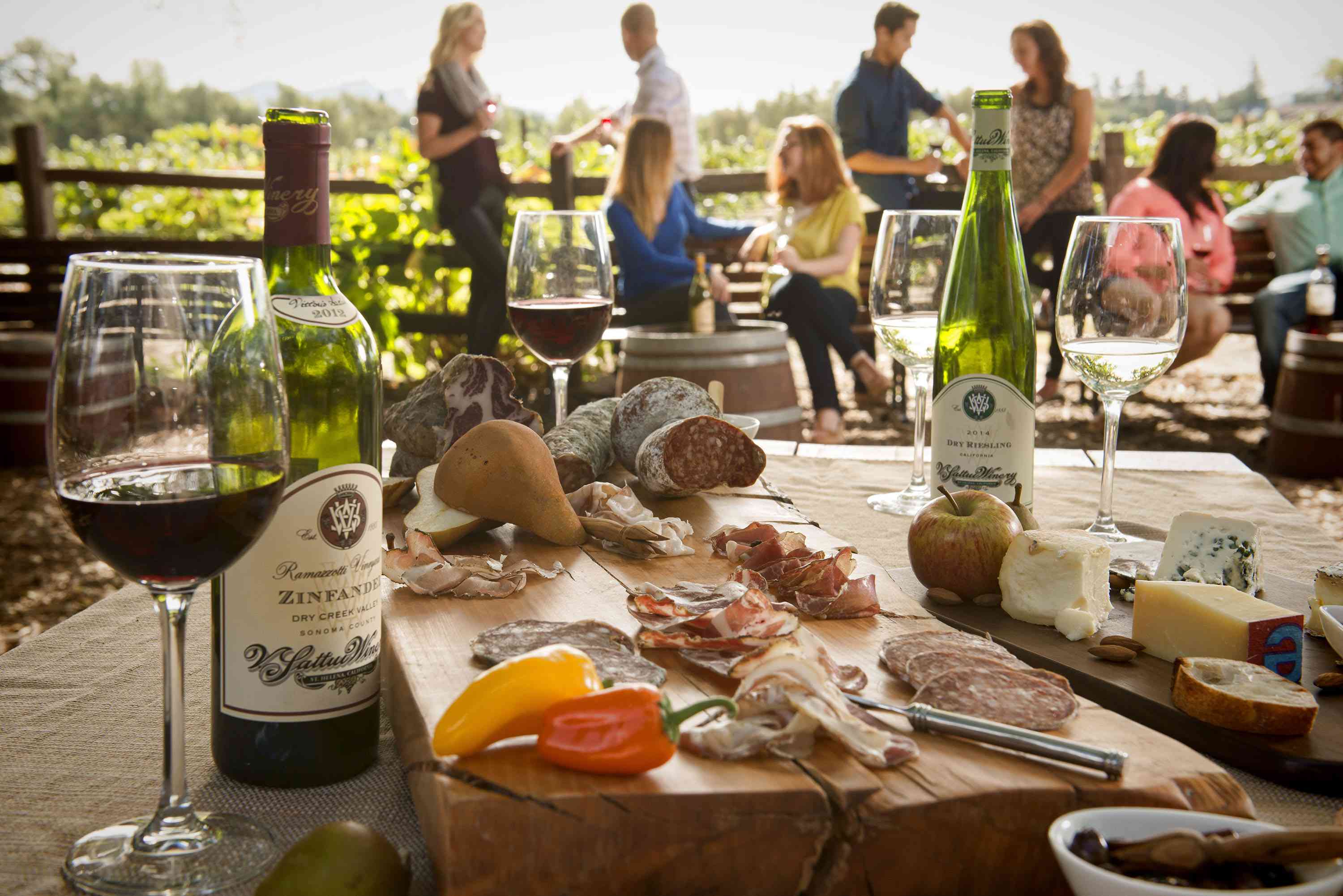 一张桌子用酒和charcuterie与一群人在背景中